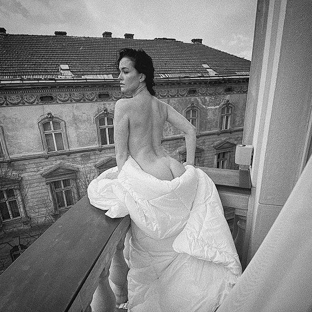 Даша Астафьева стоит спиной голая в одеяле на балконе