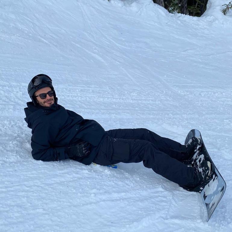Дэвид Бекхэм лежит на снегу со сноубордом