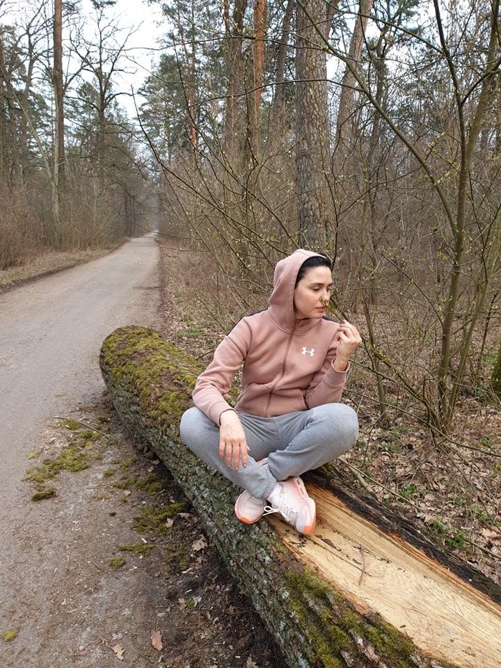 Людмила Барбир сидит на сломанном дереве в лесу