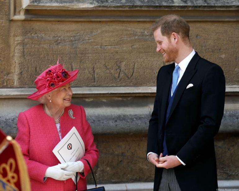 Королева и принц Гарри стоят у кирпичной стены