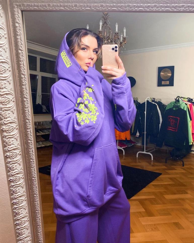 Анна Седокова стоит в фиолетовом спортивном костюме дома
