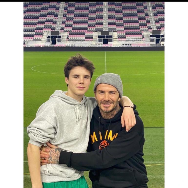 Дэвид Бекхэм с младшим сыном Крузом стоят на футбольном поле