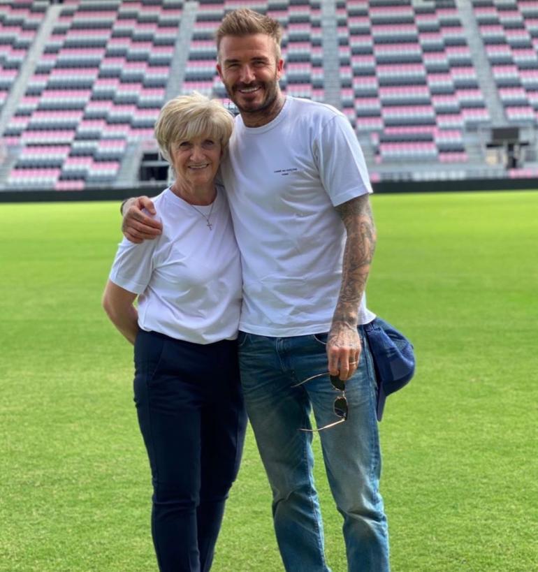 Дэвид Бекхэм с мамой стоит на футбольном поле
