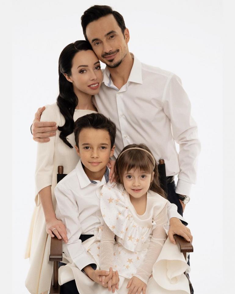 Екатерина Кухар с семьей на белом фоне стоит