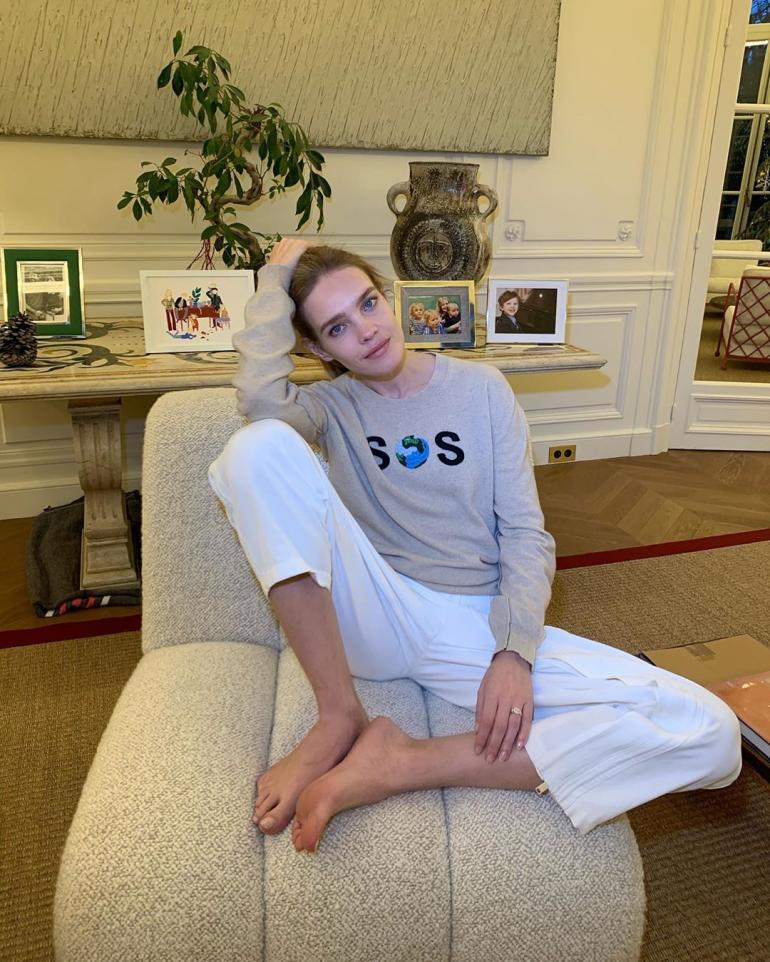 Наталья Водянова  сидит на кресле в комнате