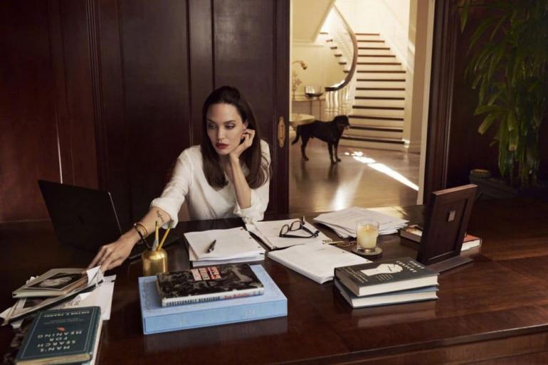 Анджелина Джоли силит за столом в кабинете
