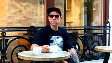 Сергей Михалок в модной кепке сидит в ресторанчике и пьет кофе